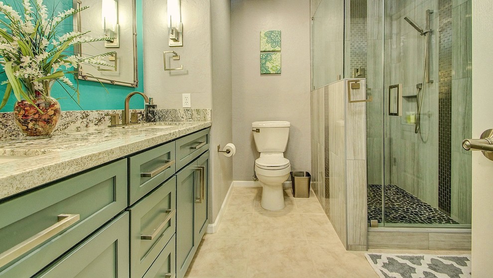 Modern inredning av ett litet badrum med dusch, med porslinskakel, klinkergolv i porslin, granitbänkskiva, släta luckor, turkosa skåp, en hörndusch, en toalettstol med separat cisternkåpa, grå kakel, grå väggar och ett undermonterad handfat