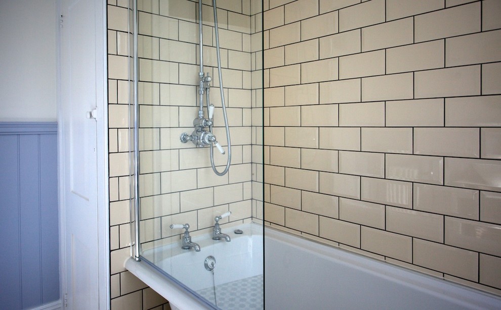 Bild på ett mellanstort shabby chic-inspirerat badrum för barn, med ett konsol handfat, möbel-liknande, skåp i slitet trä, ett badkar med tassar, en dusch/badkar-kombination, en toalettstol med separat cisternkåpa, flerfärgad kakel och beige väggar