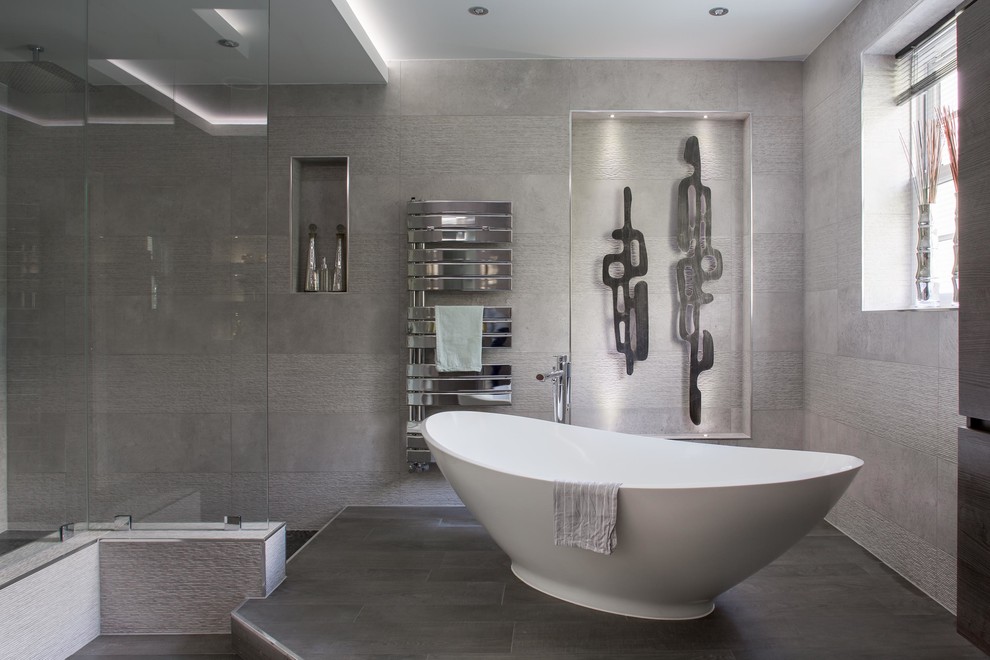 Large contemporary ensuite bathroom in Surrey with freestanding cabinets, dark wood cabinets, a freestanding bath, a walk-in shower, grey tiles, ceramic tiles, grey walls, porcelain flooring, a console sink, black floors and an open shower.