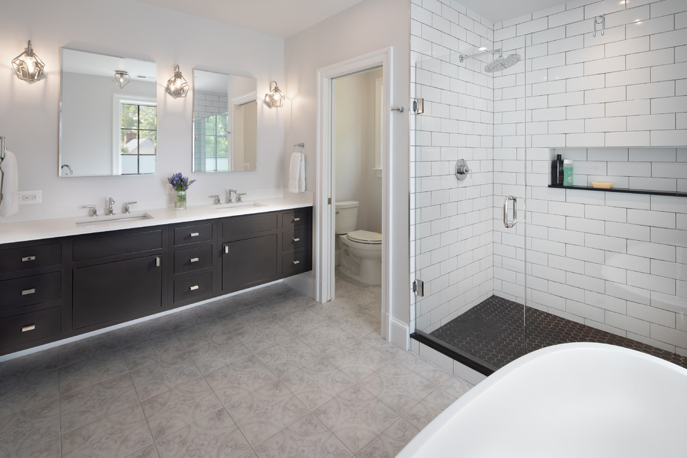 Inspiration for a large traditional ensuite bathroom in DC Metro with flat-panel cabinets, black cabinets, a freestanding bath, an alcove shower, white tiles, metro tiles, grey walls, a submerged sink, grey floors, a hinged door and white worktops.