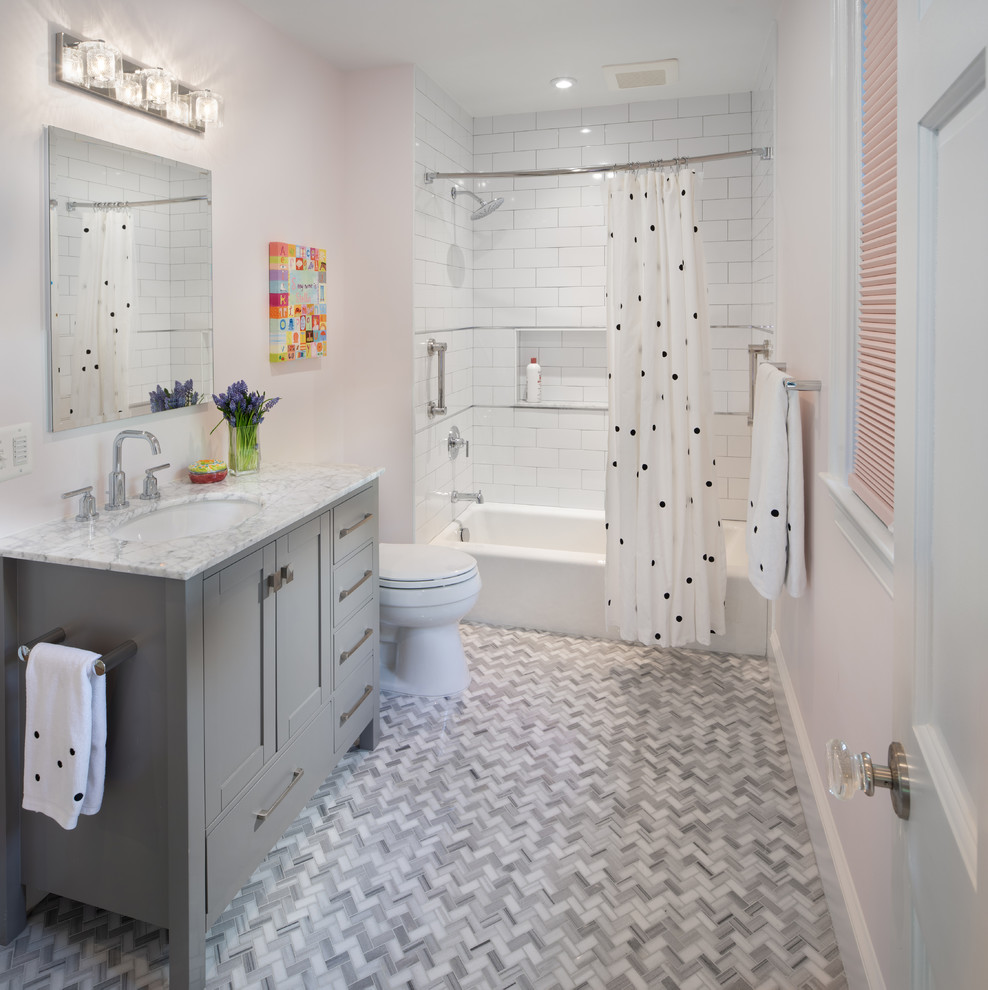 На фото: детская ванная комната в стиле неоклассика (современная классика) с фасадами в стиле шейкер, серыми фасадами, ванной в нише, душем над ванной, белой плиткой, плиткой кабанчик, розовыми стенами, полом из мозаичной плитки, врезной раковиной, серым полом, шторкой для ванной и белой столешницей