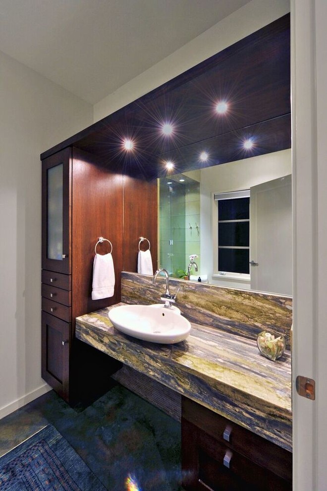 Photo of a medium sized modern shower room bathroom in Other with dark wood cabinets, an alcove shower, a one-piece toilet, white walls, a vessel sink, quartz worktops, concrete flooring and flat-panel cabinets.