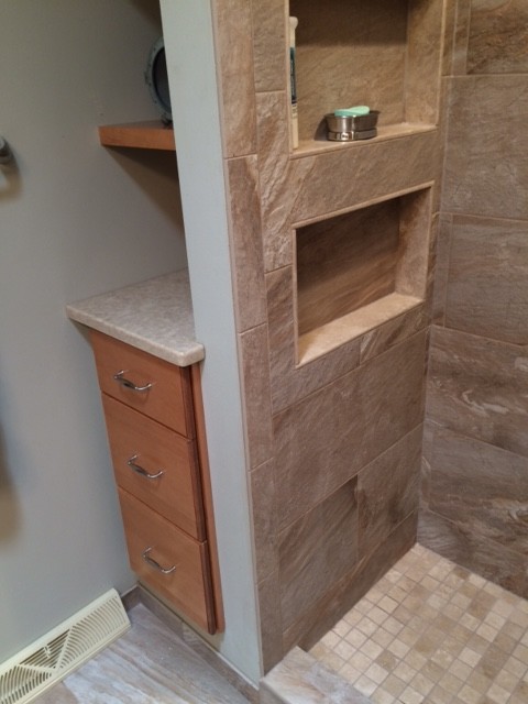Photo of a classic shower room bathroom in Milwaukee with raised-panel cabinets, medium wood cabinets, an alcove shower, a two-piece toilet, brown tiles, porcelain tiles, grey walls, porcelain flooring, a submerged sink and engineered stone worktops.