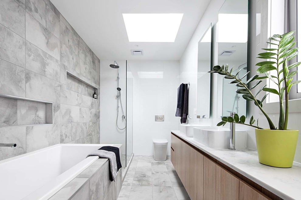Inspiration för ett stort funkis en-suite badrum, med skåp i ljust trä, ett platsbyggt badkar, en öppen dusch, en vägghängd toalettstol, grå kakel, vita väggar och klinkergolv i keramik