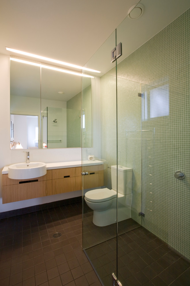 Modelo de cuarto de baño infantil minimalista de tamaño medio con armarios con paneles lisos, puertas de armario de madera clara, encimera de laminado, lavabo sobreencimera, sanitario de una pieza, baldosas y/o azulejos verdes, baldosas y/o azulejos en mosaico y paredes blancas