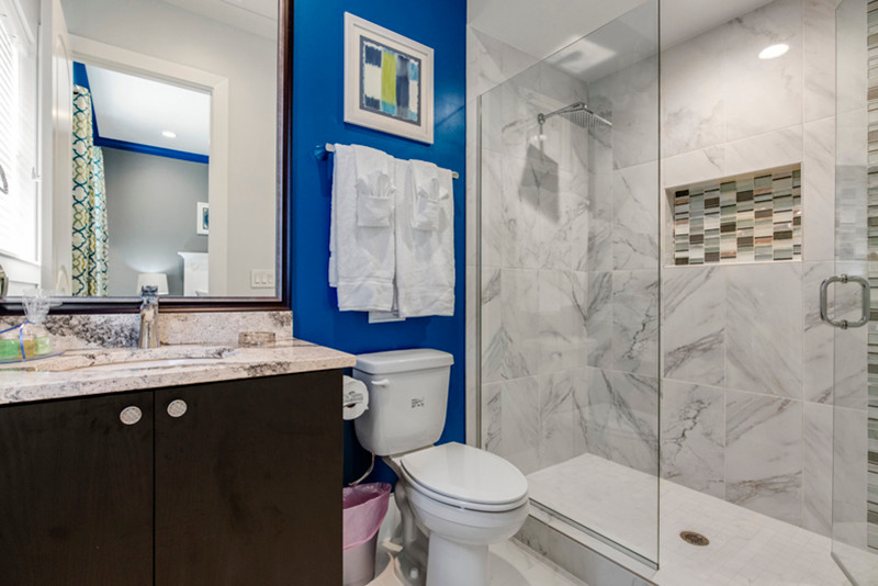 Idéer för att renovera ett litet funkis badrum med dusch, med släta luckor, skåp i mörkt trä, en dusch i en alkov, en toalettstol med separat cisternkåpa, flerfärgad kakel, glaskakel, blå väggar, klinkergolv i porslin, ett nedsänkt handfat och bänkskiva i kvarts