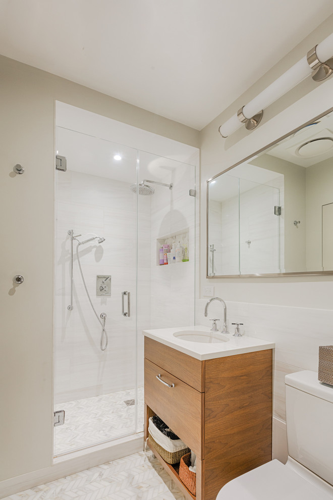 Idéer för att renovera ett mellanstort funkis vit vitt badrum med dusch, med släta luckor, skåp i mellenmörkt trä, en dusch i en alkov, en toalettstol med hel cisternkåpa, vit kakel, keramikplattor, grå väggar, marmorgolv, ett undermonterad handfat, bänkskiva i kvarts, flerfärgat golv och dusch med gångjärnsdörr