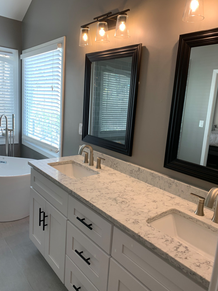 Medium sized traditional ensuite bathroom in Atlanta with shaker cabinets, white cabinets, a freestanding bath, a corner shower, a two-piece toilet, grey tiles, metro tiles, grey walls, porcelain flooring, a submerged sink, engineered stone worktops, grey floors, a hinged door, white worktops, a wall niche, double sinks, a built in vanity unit and a vaulted ceiling.
