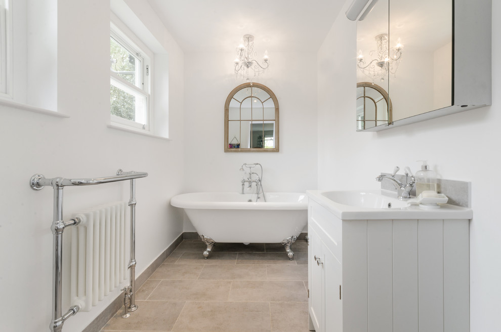 Пример оригинального дизайна: главная ванная комната среднего размера в стиле шебби-шик с белыми фасадами, белыми стенами, бежевым полом, ванной на ножках, монолитной раковиной, белой столешницей и фасадами в стиле шейкер