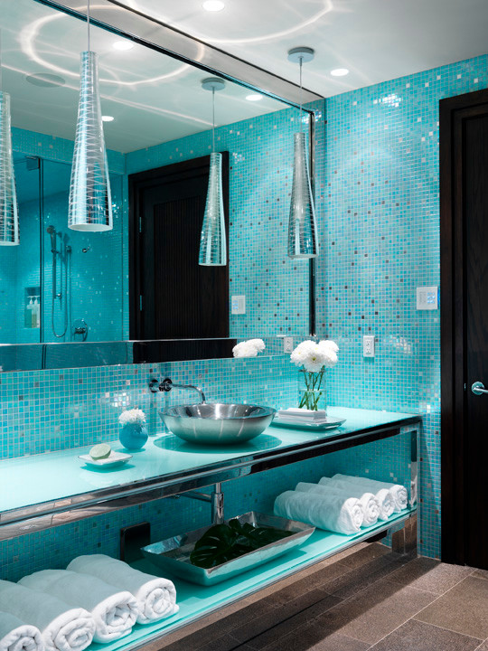 Cette image montre une grande salle d'eau design avec un placard sans porte, des portes de placard bleues, une douche double, WC à poser, un carrelage bleu, mosaïque, un mur bleu, sol en béton ciré, une vasque et un plan de toilette en verre.