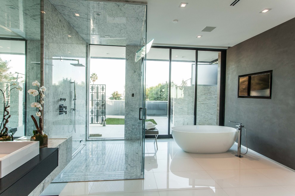 Diseño de cuarto de baño principal actual con bañera exenta, ducha a ras de suelo, paredes grises, lavabo sobreencimera y ducha con puerta con bisagras