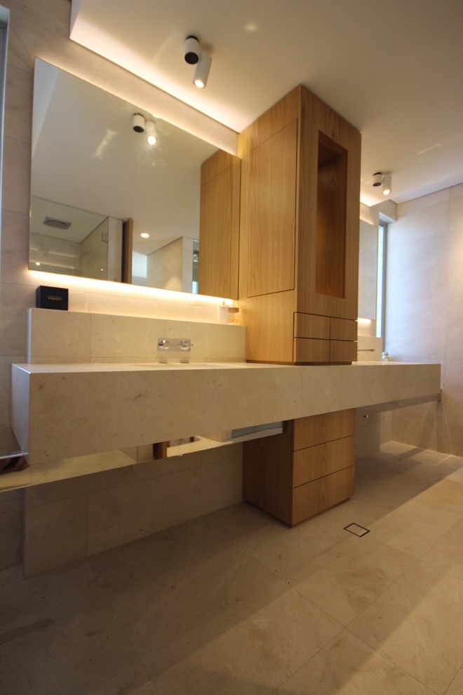 Diseño de cuarto de baño minimalista con sanitario de pared, baldosas y/o azulejos de travertino, lavabo bajoencimera y encimera de piedra caliza