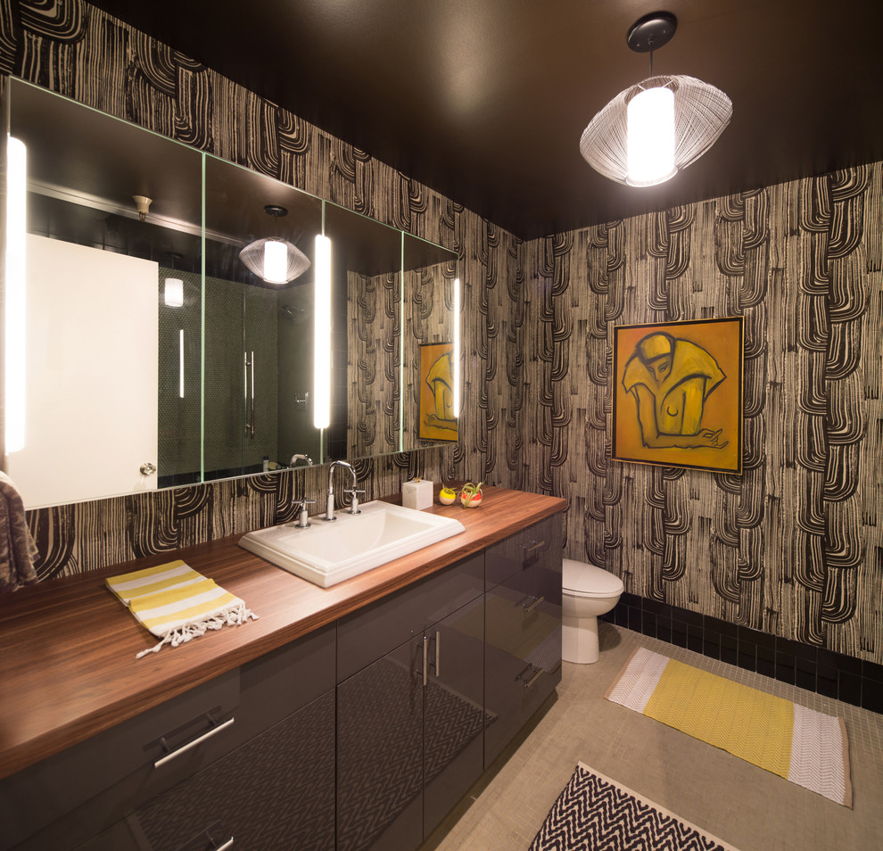 Diseño de cuarto de baño contemporáneo con lavabo encastrado, armarios con paneles lisos, puertas de armario grises, encimera de madera y paredes multicolor
