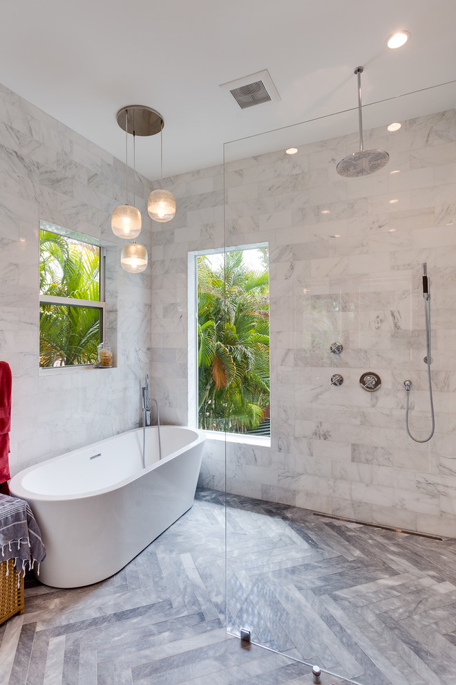 This is an example of a contemporary bathroom in Miami with a freestanding bath, a walk-in shower, white tiles, marble tiles and grey floors.