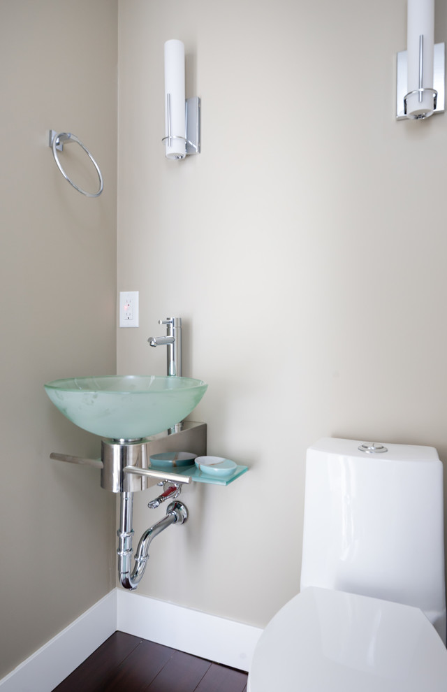 Imagen de cuarto de baño actual pequeño con sanitario de una pieza, suelo laminado, aseo y ducha, lavabo tipo consola, encimera de vidrio, suelo marrón y encimeras azules
