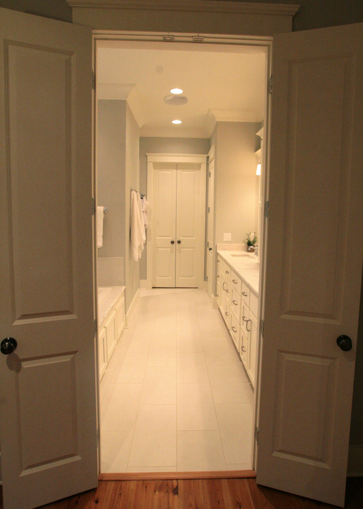 Свежая идея для дизайна: большая главная ванная комната в стиле кантри с плоскими фасадами, белыми фасадами, гидромассажной ванной, угловым душем, унитазом-моноблоком, белой плиткой, керамогранитной плиткой, серыми стенами, полом из керамогранита, накладной раковиной и мраморной столешницей - отличное фото интерьера