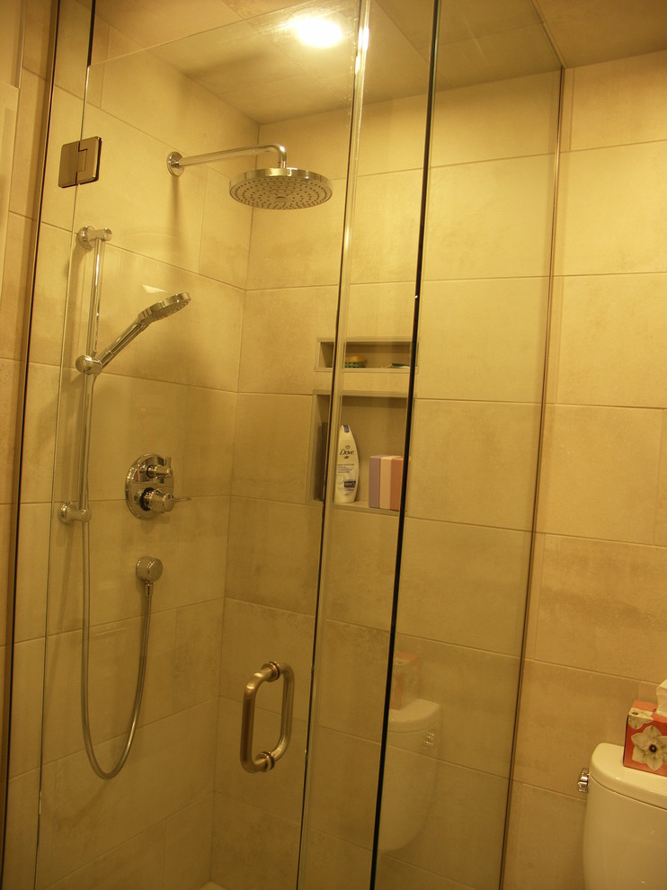 This is an example of a small contemporary shower room bathroom in Edmonton with an alcove shower, a two-piece toilet, beige tiles, porcelain tiles, beige walls, ceramic flooring, beige floors and a hinged door.