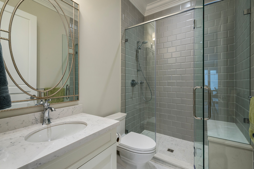 Пример оригинального дизайна: ванная комната среднего размера в классическом стиле с фасадами с утопленной филенкой, белыми фасадами, душем в нише, унитазом-моноблоком, серой плиткой, керамической плиткой, белыми стенами, полом из керамогранита, душевой кабиной, врезной раковиной, столешницей из искусственного кварца, серым полом и душем с распашными дверями