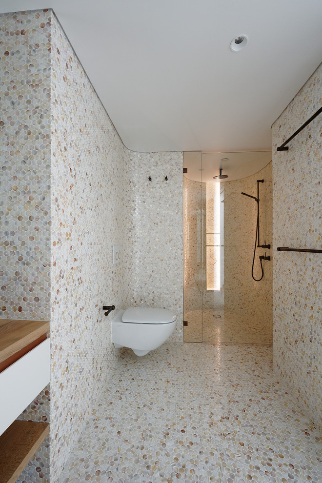 Exempel på ett stort modernt badrum med dusch, med vita skåp, en vägghängd toalettstol, flerfärgad kakel, mosaik, flerfärgade väggar, mosaikgolv, ett fristående handfat, träbänkskiva, flerfärgat golv, dusch med gångjärnsdörr, släta luckor och en dusch i en alkov