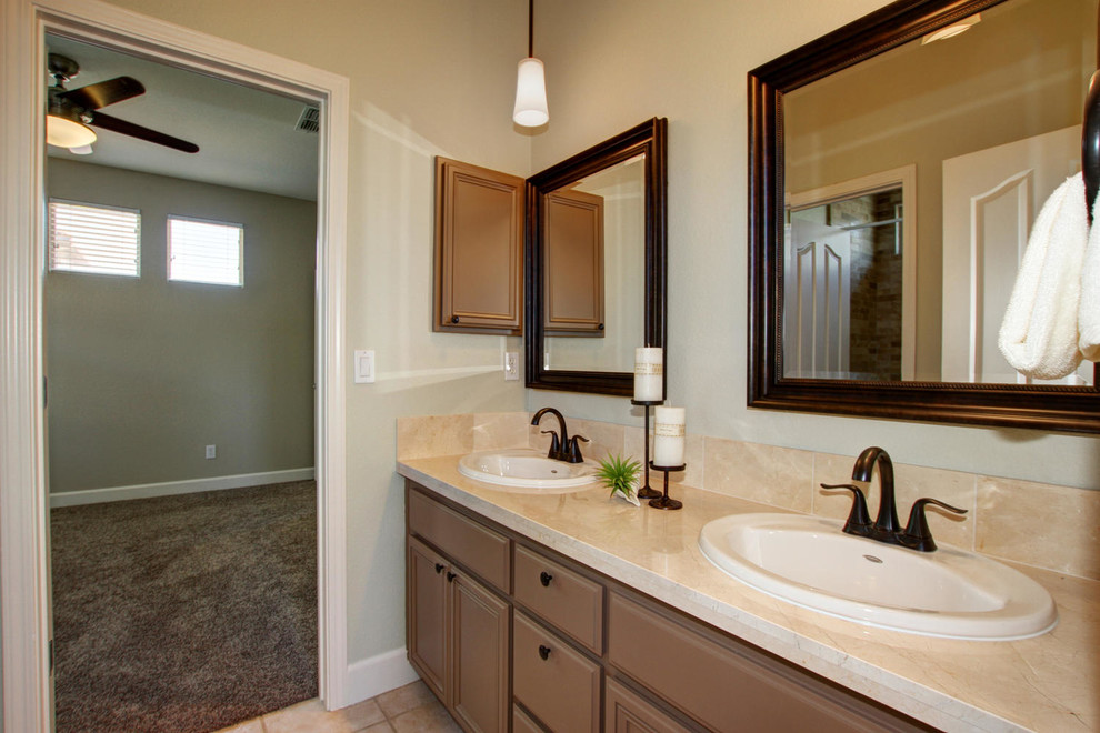 Bild på ett badrum, med ett nedsänkt handfat, släta luckor, bruna skåp, marmorbänkskiva och ett hörnbadkar