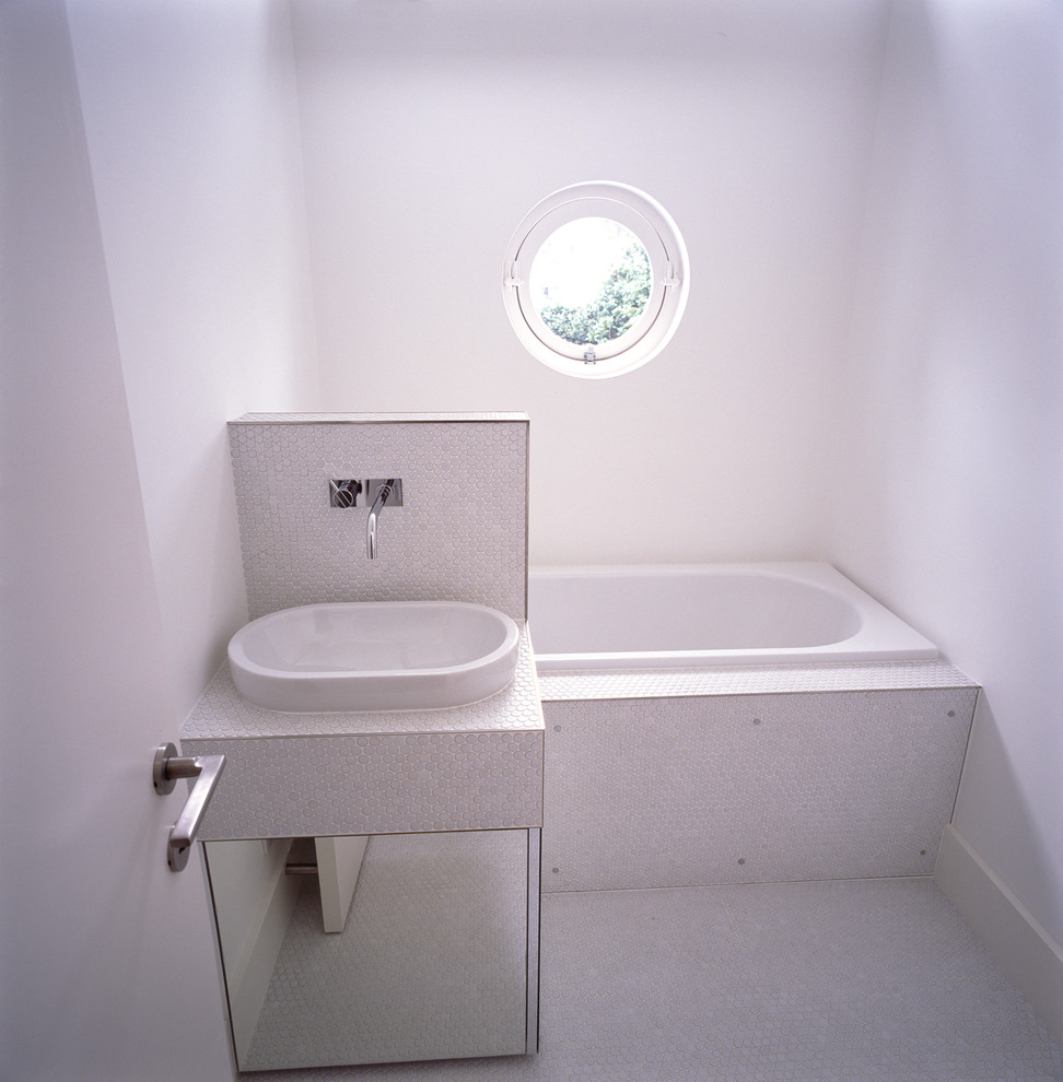 Idee per una stanza da bagno padronale minimal di medie dimensioni con ante lisce, vasca da incasso, WC sospeso, pareti bianche, pavimento con piastrelle a mosaico, lavabo da incasso, top piastrellato, pavimento bianco e top bianco