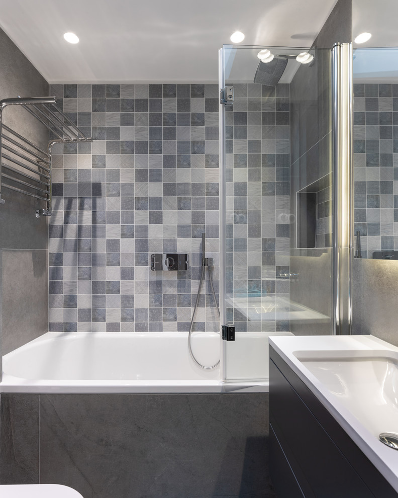 На фото: ванная комната в современном стиле с плоскими фасадами, серыми фасадами, ванной в нише, душем над ванной, серой плиткой, серыми стенами, врезной раковиной, душем с распашными дверями и белой столешницей
