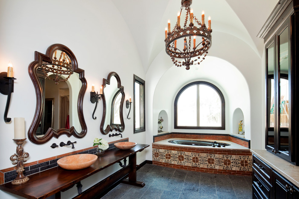 Diseño de cuarto de baño principal mediterráneo con lavabo sobreencimera, puertas de armario de madera en tonos medios, encimera de madera, bañera encastrada sin remate, baldosas y/o azulejos multicolor, paredes blancas y ventanas