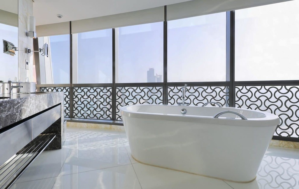 Modelo de cuarto de baño principal contemporáneo grande con bañera exenta, suelo de cemento, lavabo integrado, encimera de mármol, suelo blanco y encimeras negras