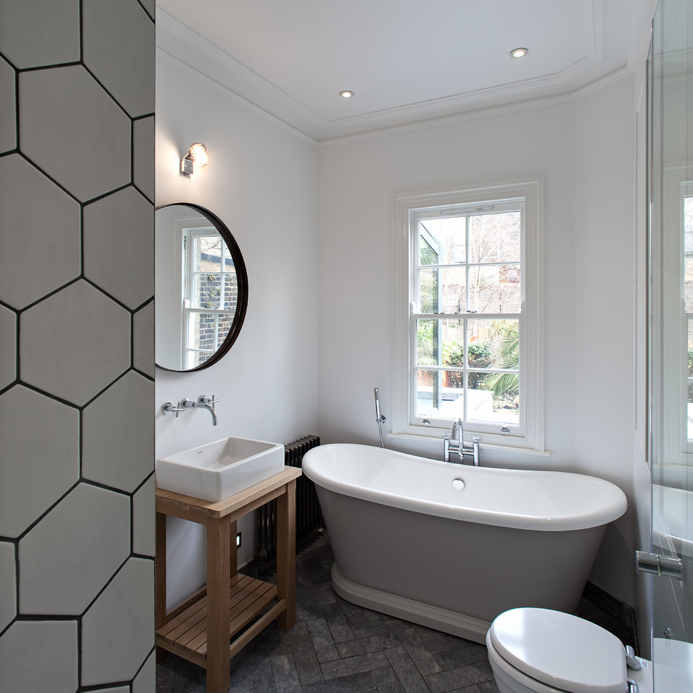 Modernes Badezimmer mit Aufsatzwaschbecken, hellbraunen Holzschränken, freistehender Badewanne, weißer Wandfarbe und offenen Schränken in London