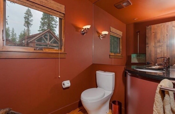 Amerikansk inredning av ett litet badrum med dusch, med släta luckor, skåp i mellenmörkt trä, en dusch i en alkov, en toalettstol med separat cisternkåpa, röd kakel, röda väggar, mellanmörkt trägolv, ett väggmonterat handfat, granitbänkskiva, gult golv och dusch med gångjärnsdörr