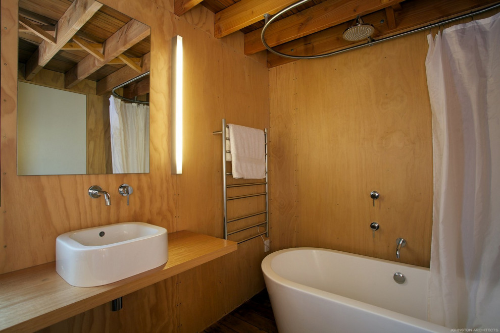 Photo of a small industrial ensuite bathroom in Christchurch with a shower/bath combination, light hardwood flooring, wooden worktops, a shower curtain, a single sink, a floating vanity unit, exposed beams and wainscoting.