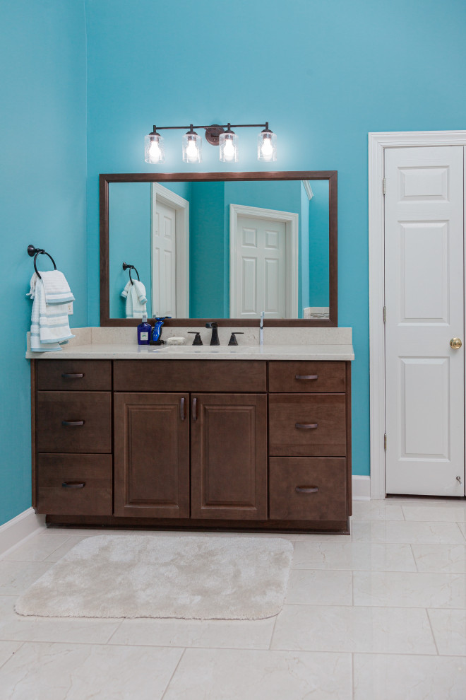Exemple d'une salle de bain principale tendance en bois brun de taille moyenne avec un placard à porte plane, une baignoire posée, des carreaux de porcelaine, un mur bleu, un sol en carrelage de porcelaine, un lavabo encastré, un plan de toilette en quartz modifié, une cabine de douche à porte battante, un banc de douche, meuble double vasque, meuble-lavabo encastré et un plafond voûté.