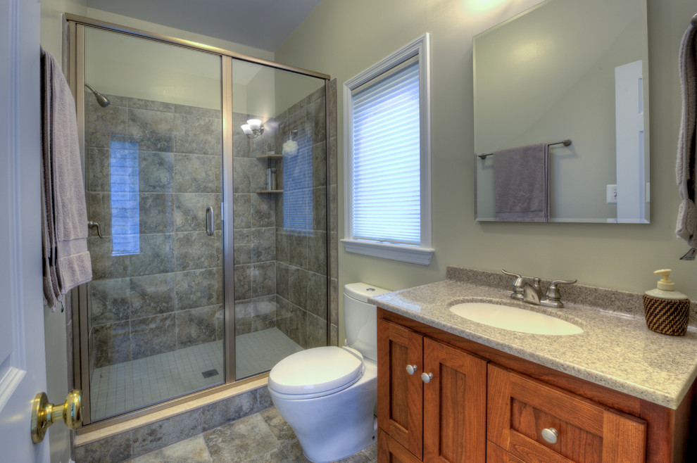 Idées déco pour une salle de bain classique en bois brun de taille moyenne avec un carrelage gris, un mur gris, un placard à porte shaker, WC séparés, un sol en ardoise, un lavabo encastré et un plan de toilette en surface solide.