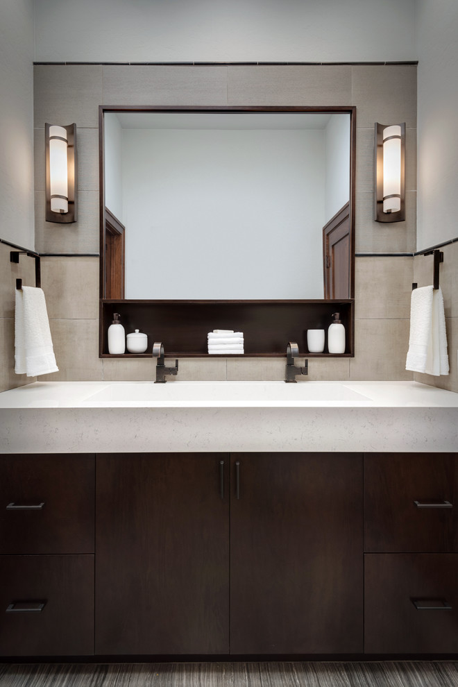 Mid-sized trendy master gray tile and porcelain tile porcelain tile bathroom photo in Phoenix with flat-panel cabinets, dark wood cabinets, a one-piece toilet, a trough sink, quartz countertops and beige walls