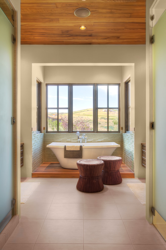 Idée de décoration pour une salle de bain chalet en bois foncé avec une baignoire indépendante, un carrelage vert et une fenêtre.