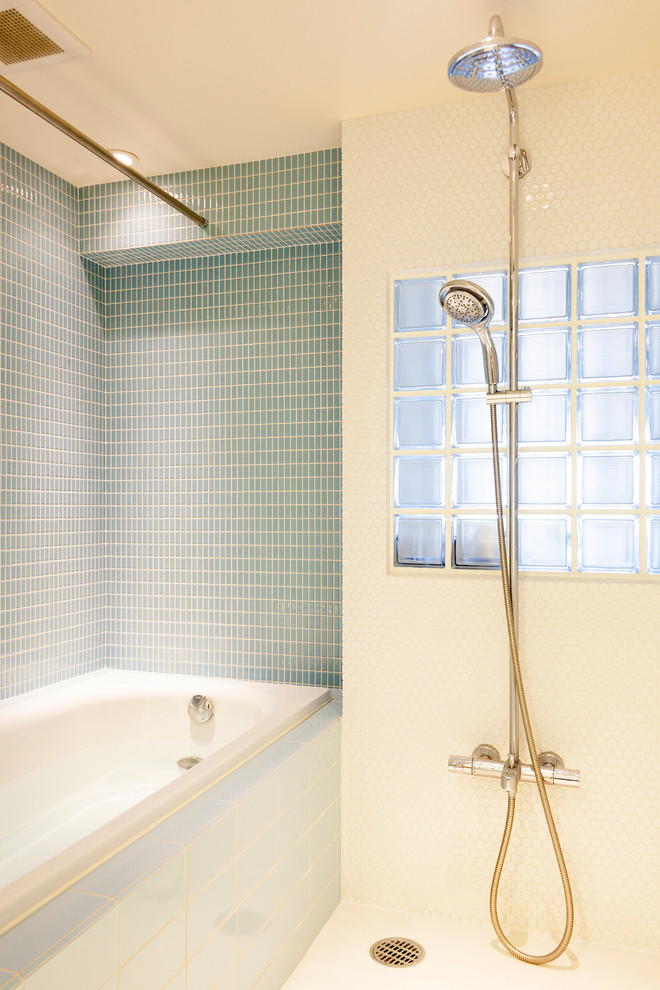東京23区にある中くらいなおしゃれなマスターバスルーム (ドロップイン型浴槽、ダブルシャワー、青いタイル、ガラスタイル、白い壁、モザイクタイル) の写真