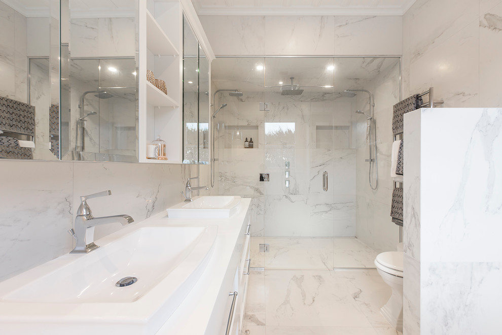 Large traditional shower room bathroom in Hamilton with recessed-panel cabinets, white cabinets, a double shower, a wall mounted toilet, white tiles, stone tiles, multi-coloured walls, marble flooring, a built-in sink and solid surface worktops.