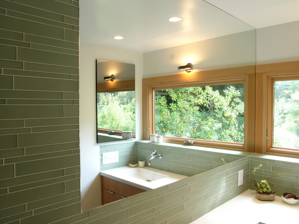 Свежая идея для дизайна: ванная комната в стиле модернизм с врезной раковиной, плоскими фасадами, фасадами цвета дерева среднего тона, зеленой плиткой и удлиненной плиткой - отличное фото интерьера