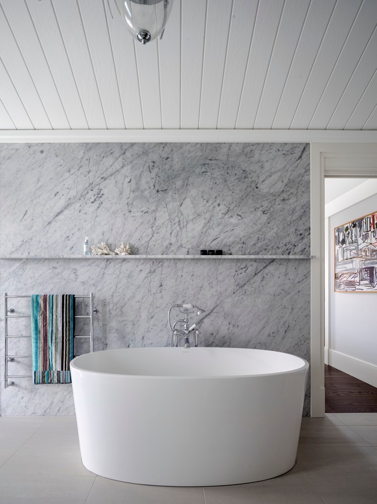 Cette image montre une salle de bain marine de taille moyenne avec une baignoire indépendante et du carrelage en marbre.