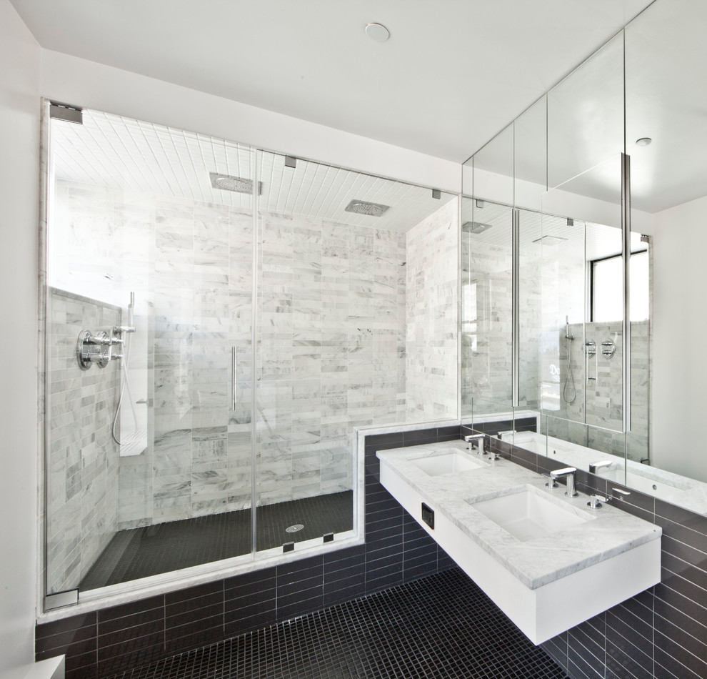 Modelo de cuarto de baño actual con lavabo bajoencimera, ducha empotrada, baldosas y/o azulejos grises, suelo con mosaicos de baldosas y suelo negro
