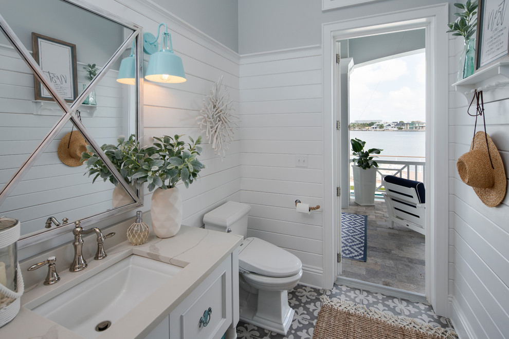 Maritimes Badezimmer mit weißen Schränken, Wandtoilette mit Spülkasten, grauer Wandfarbe, Unterbauwaschbecken, grauem Boden, weißer Waschtischplatte und Schrankfronten mit vertiefter Füllung in Tampa