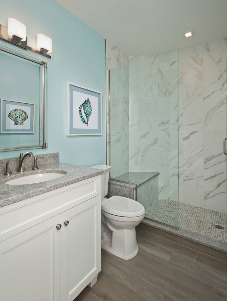 Modelo de cuarto de baño costero con puertas de armario blancas, paredes azules y encimeras grises