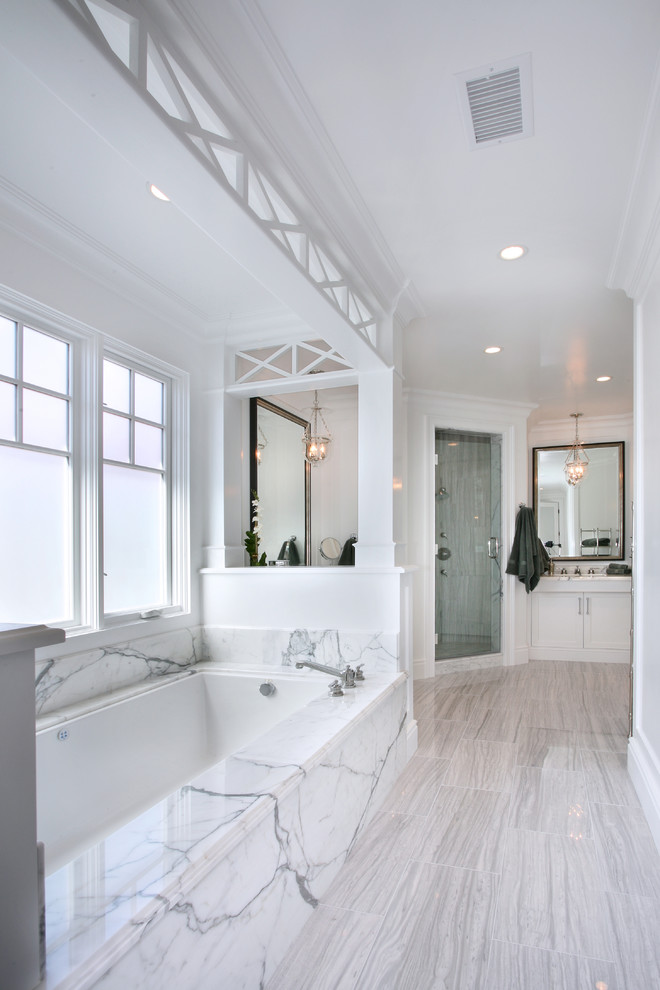 На фото: главная ванная комната среднего размера в морском стиле с белыми фасадами, мраморной столешницей, белыми стенами, фасадами с утопленной филенкой, полновстраиваемой ванной, душем в нише, белой плиткой, мраморной плиткой, полом из керамогранита, врезной раковиной, серым полом и душем с распашными дверями