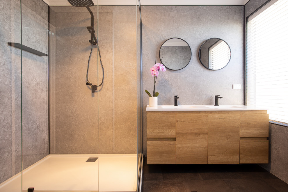 Cette image montre une salle de bain principale minimaliste de taille moyenne avec une douche d'angle, un carrelage gris, des dalles de pierre, un mur gris, un sol en vinyl, un plan de toilette en quartz modifié, un sol noir, une cabine de douche à porte battante et un plan de toilette blanc.