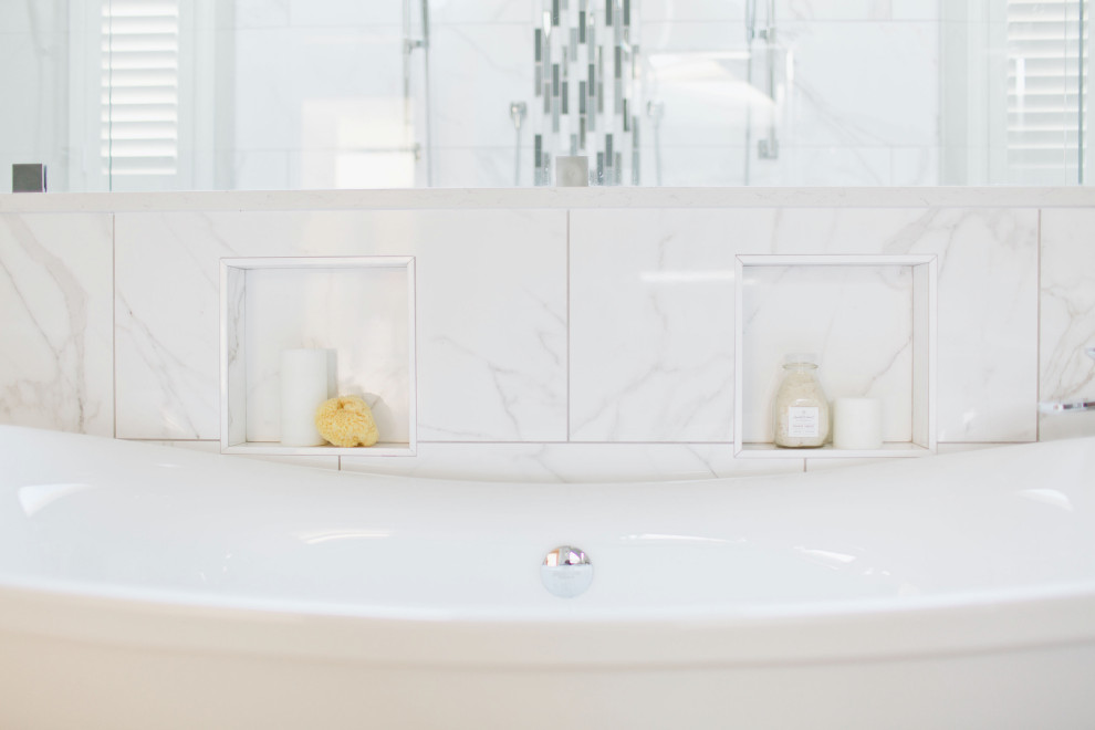 Пример оригинального дизайна: большая главная ванная комната в стиле неоклассика (современная классика) с фасадами с декоративным кантом, темными деревянными фасадами, отдельно стоящей ванной, двойным душем, унитазом-моноблоком, белой плиткой, керамогранитной плиткой, серыми стенами, полом из керамогранита, врезной раковиной, столешницей из искусственного кварца, серым полом, душем с распашными дверями и белой столешницей