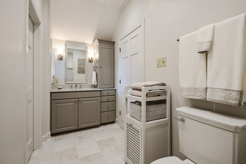 Bild på ett mellanstort vintage en-suite badrum, med luckor med upphöjd panel, grå skåp, en kantlös dusch, en toalettstol med separat cisternkåpa, grå kakel, porslinskakel, grå väggar, klinkergolv i porslin, ett undermonterad handfat, bänkskiva i kvarts och grått golv
