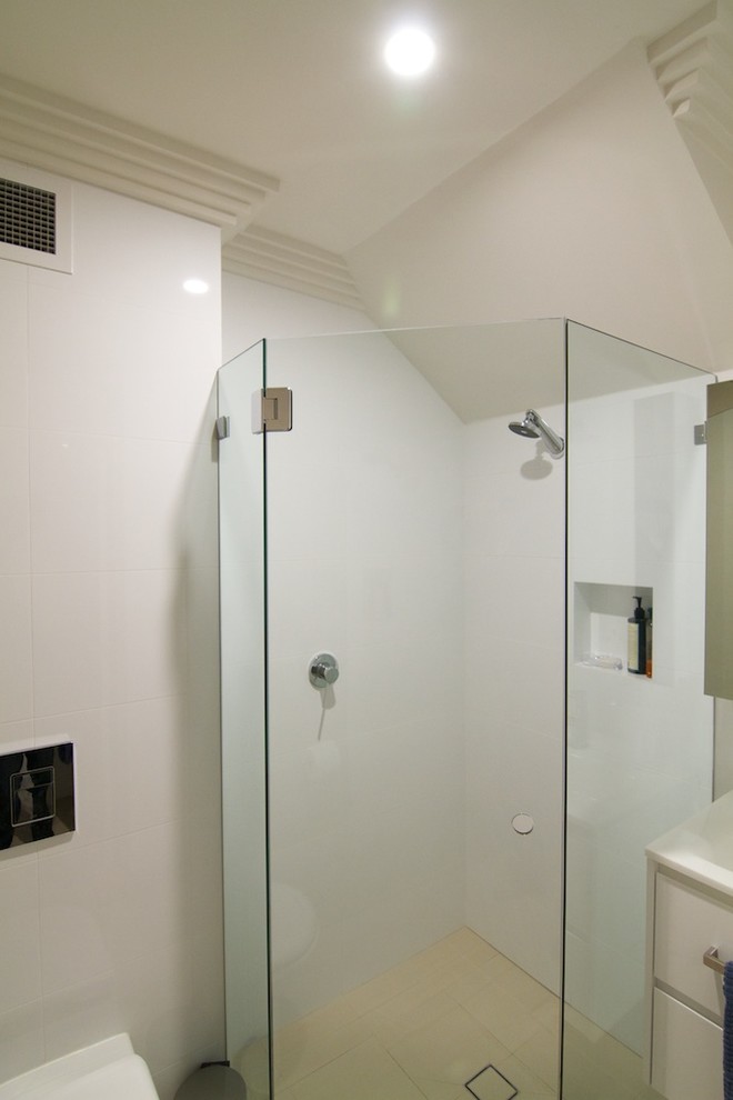 Idéer för ett mellanstort modernt vit badrum med dusch, med släta luckor, beige skåp, travertin golv, beiget golv, en hörndusch, en vägghängd toalettstol, vit kakel, keramikplattor, vita väggar, ett integrerad handfat, bänkskiva i kvarts och dusch med gångjärnsdörr