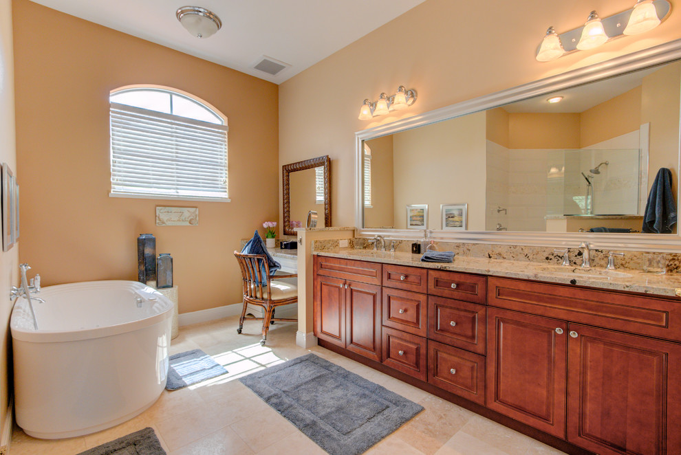Exempel på ett mellanstort klassiskt beige beige en-suite badrum, med luckor med upphöjd panel, skåp i mellenmörkt trä, ett fristående badkar, beige kakel, beige väggar, ett undermonterad handfat, granitbänkskiva och beiget golv