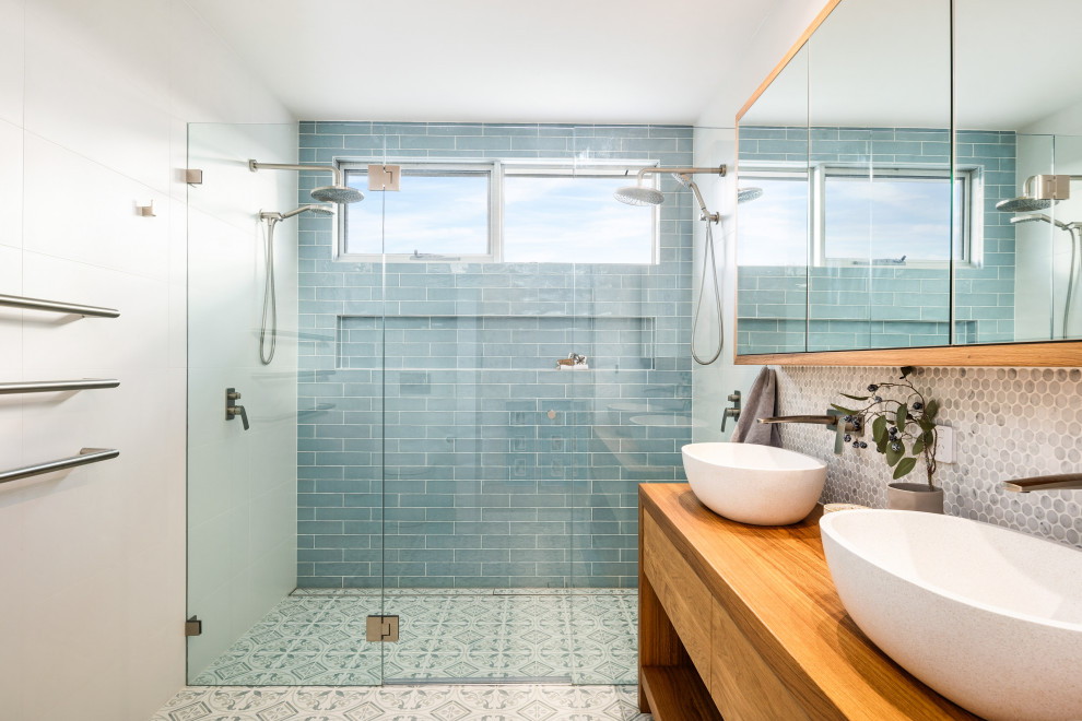 This is an example of a large nautical ensuite bathroom in Wollongong with open cabinets, medium wood cabinets, a freestanding bath, a corner shower, beige tiles, porcelain tiles, beige walls, porcelain flooring, a vessel sink, wooden worktops, beige floors, a hinged door, brown worktops and double sinks.