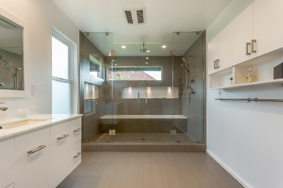 Großes Modernes Badezimmer En Suite mit grauen Schränken, braunen Fliesen, weißer Wandfarbe, Keramikboden, integriertem Waschbecken, Quarzwerkstein-Waschtisch, flächenbündigen Schrankfronten, Duschnische, Porzellanfliesen, grauem Boden und Falttür-Duschabtrennung in Los Angeles